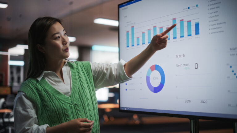 Young woman points to a bar graph displaying the importance of data analytics for social services.