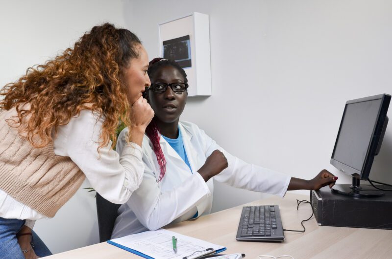 Two human services professionals reviewing case data together on a computer to improve Medicaid program outcomes.